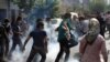 Iranian protesters run from tear gas at an opposition rally in Tehran on July 9