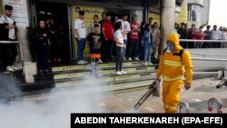 Iranians take pictures of firefighters as they disinfect streets in an effort to stop the wild spread of coronavirus (COVID-19) in Tehran. March 13, 2020.