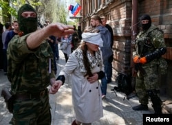 Проросійськи налаштований озброєний чоловік проводить українську журналістку Ірму Крат після прес-конференції у Слов'янську, 21 квітня 2014 року