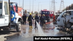 Firefighters clean the scene where two cars exploded in Kut on July 29, killing five people and wounding more than 30 others.