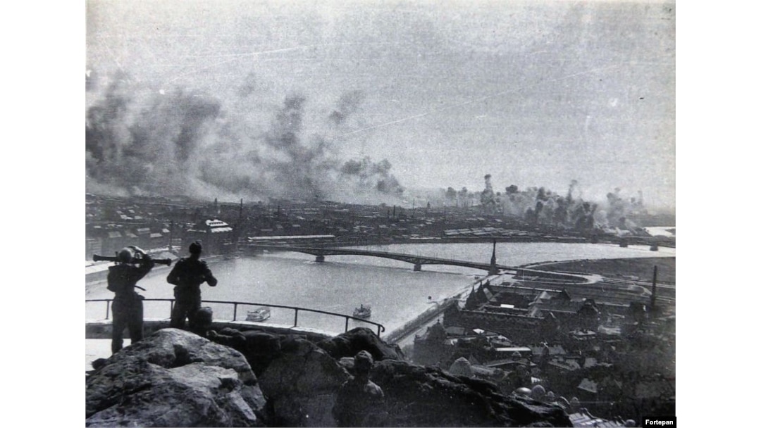 Hungarian soldiers with a range finder watch from Gellert Hill as bombs from an American air raid pummel Nazi-occupied Budapest in 1944.