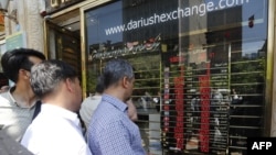 Iranians check exchange rates outside a bank in Tehran. The country's currency, the rial, has lost 70 percent of its value in recent years, causing much economic hardship. (file photo)