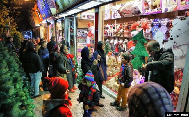 Iranians are seen behind Christmas decorations as they walk ouside a shop in Tehran, 22Dec2015