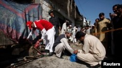 Officials and rescue workers collect evidence at the site of a bomb blast in Charsadda on April 22, 2014.