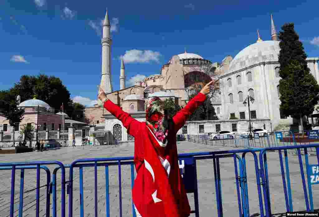 O femeie înfășurată în steagul Turciei sărbătorește în fața Hagiei Sophia după decizia judecătorească din 10 iulie. Mișcarea de a reface moscheea a atras condamnări din întreaga lume, inclusiv din partea Papei Francisc, care a spus că decizia &bdquo;i-a provocat o mare durere&rdquo;. &nbsp; &nbsp;