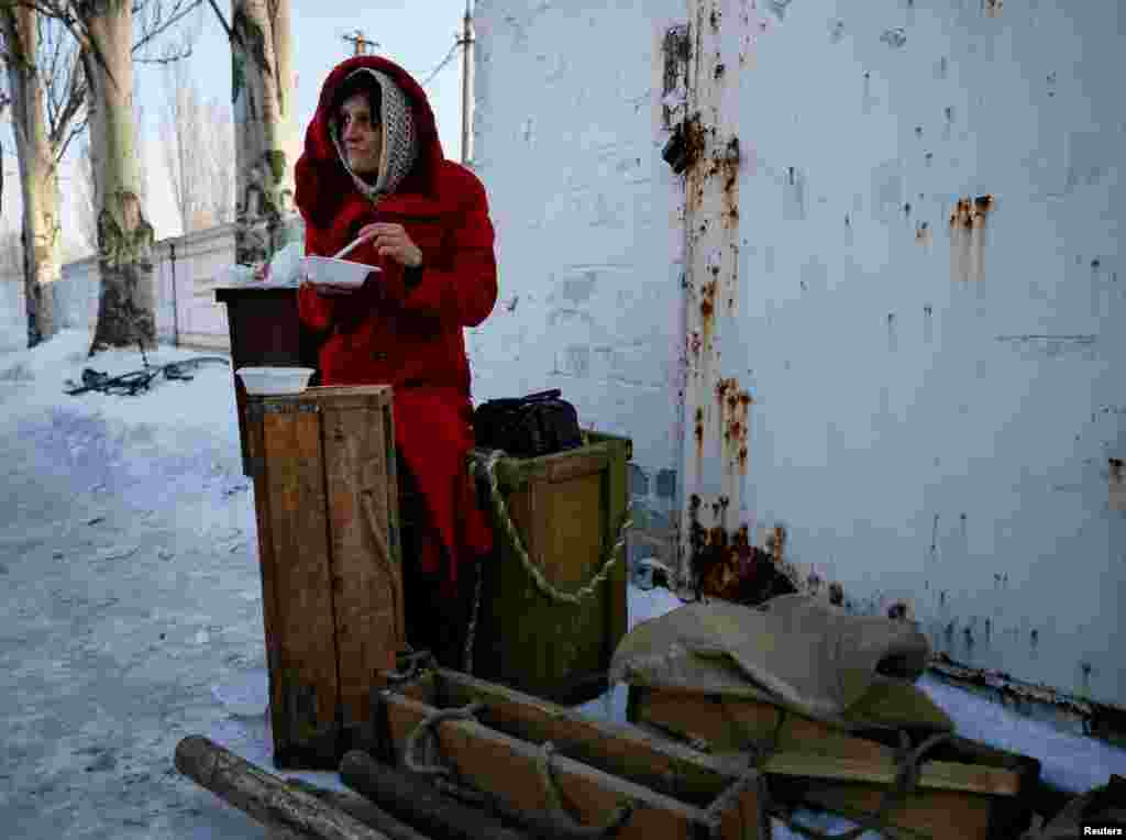 Ýerli ýaşaýjy topa tutuşlykdan soň adatdan daşary ýagdaýlar merkezinde nahar iýýär. Awdiýiwka, Ukraina, 1-nji fewral. (Reuters/Gleb Garanich)