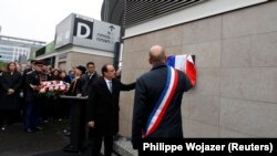 French President Francois Hollande and Saint-Denis Mayor Didier Paillard unveil a commemorative plaque outside the Stade de France stadium, in Saint-Denis, near Paris, on November 13, during a ceremony held for the victims of last year's Paris attacks, which targeted the Bataclan concert hall as well as a series of bars and killed 130 people. 