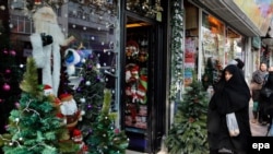 An Iranian chador clad woman passes by a Santa Claus shop in Tehran, December 22, 2014