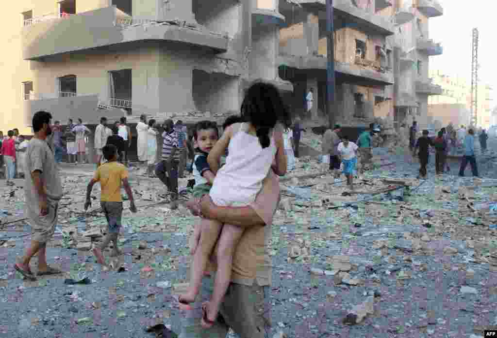 A man carries two children away from the scene of an explosion in the northern Syrian city of Raqqa. Three people were killed and dozens injured, including children. (AFP/Abdullah al-Sham)