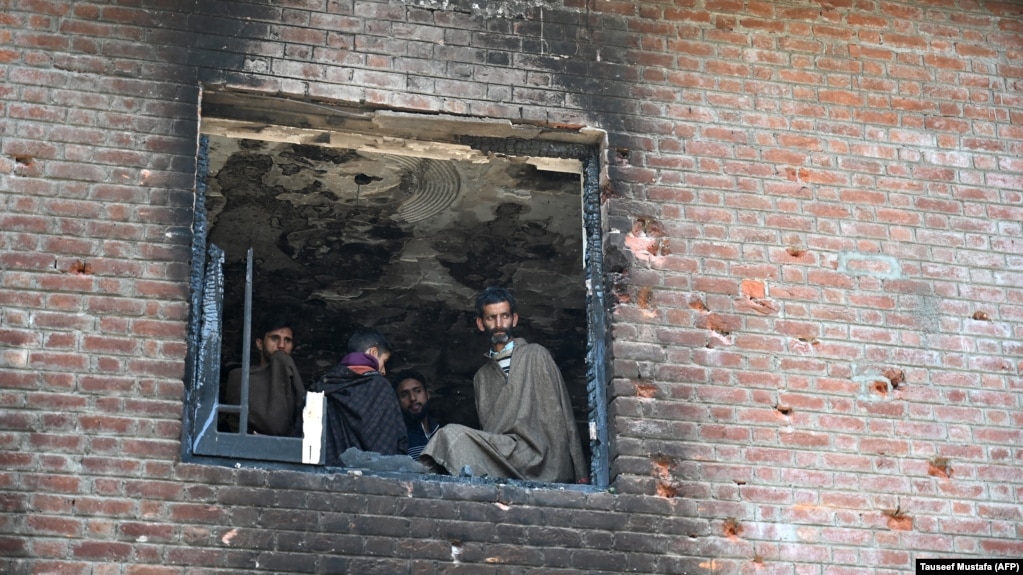 Kashmiri villagers look inside a damaged house following a gunfight between militants and Indian government forces at Panjran village in Pulwama, south of Srinagar on June 7.
