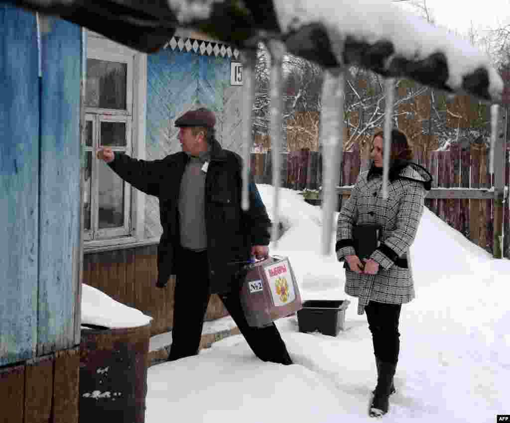 Members of a local electoral commission bring a mobile ballot to elderly people in their house in the village of Boreshino, some 40 km outside the western Russian city of Smolensk.