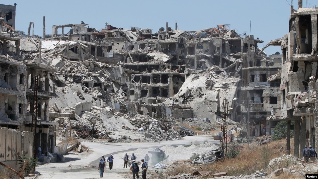 În imagine, muncitori curăță rămășițele ruinelor, în urma bombardamentelor din cartierul Wadi al-Sayeh din orașul Homs din Siria, în 2016.