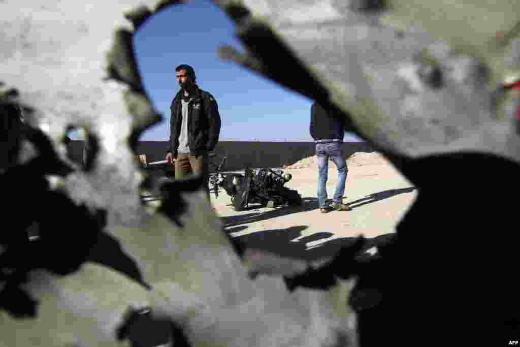 Palestinians walk past the wreckage of a motorbike whose driver was injured in an Israeli air strike on February 9 in Deir al-Balah, in the center of the Gaza Strip. (AFP/Said Khatib)