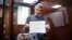 Aleksei Gorinov inside a glass cell during a hearing in his trial at a courthouse in Moscow in June 2022.