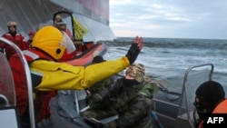 In a Greenpeace handout photo taken on September 18, a Russian Coast Guard officer (center) wields a knife at an activist during a Greenpeace attempt to climb Gazprom’s "Prirazlomnaya" Arctic oil platform in the Pechora Sea.