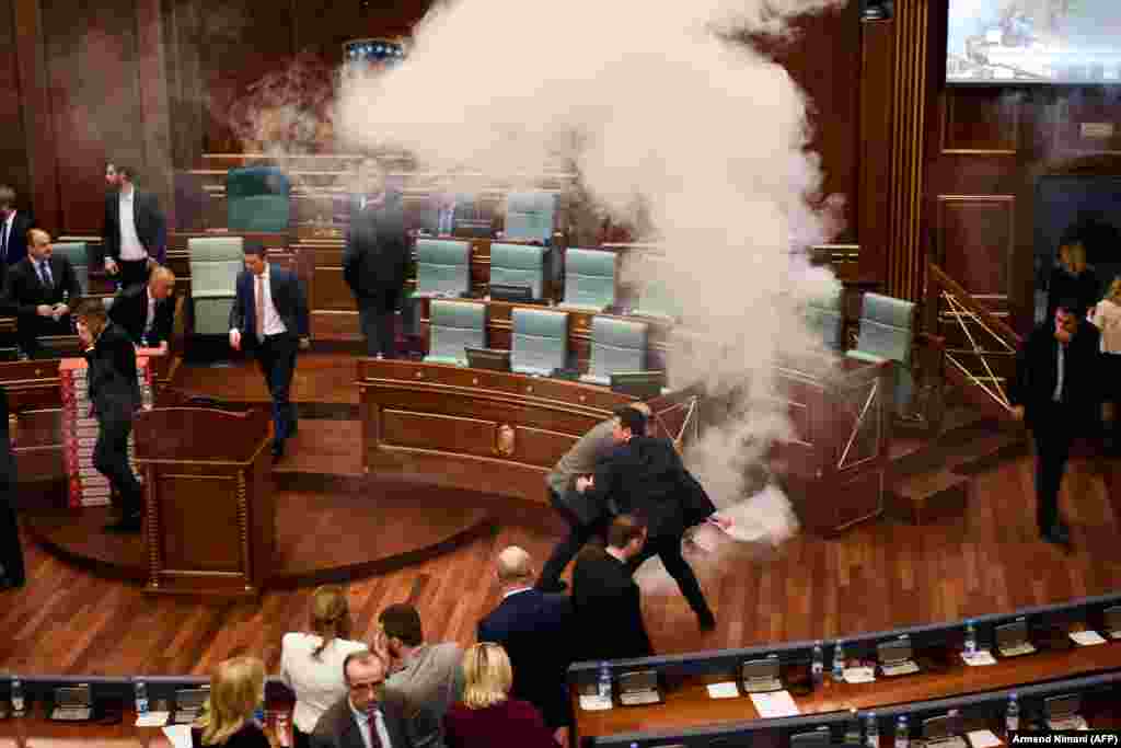 Kosovar lawmakers react after opposition members released tear gas inside the country's parliament in Pristina on March 21 before a vote on a border demarcation deal signed in 2015 with Montenegro. (AFP/Armend Nimani)