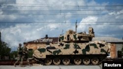 U.S. servicemen walk past a Bradley infantry fighting vehicle as they arrive for the joint U.S.-Georgian exercise Noble Partner 2016 in Vaziani.