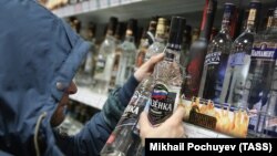 Дүкен сөрелерінен ішімдік таңдап жүрген ер адам. Көрнекі сурет. 