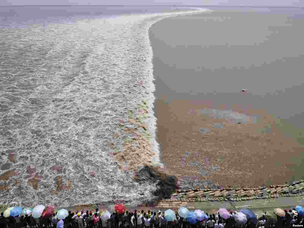 A remote-controlled helicopter hovers over the Qiantang River in China as tourists gather on the riverbank to see the soaring tide in Haining, Zhejiang Province. (Photo by Reuters) 