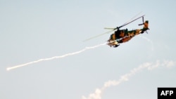 A military attack helicopter fires missiles during Syrian Army maneuvers at an undisclosed location on July 10.