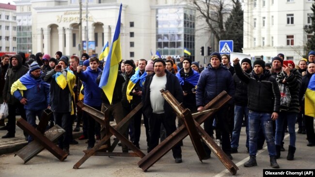 Люди стоять перед військовими Росії під час мітингу проти російської окупації. Херсон, 7 березня 2022 року