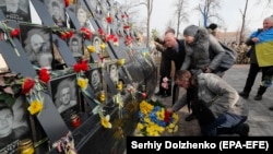 People place flowers at the memorial dedicated to people who died in the 2014 clashes with security forces on Kyiv's Independence Square on February 18, 2020.