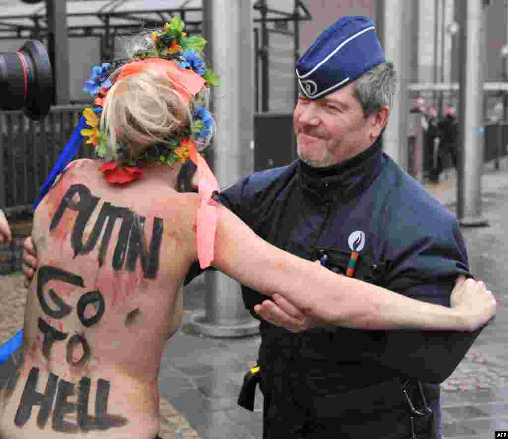 An activist of Ukraine's Femen feminist group is taken away by police as she demonstrates near the EU Council building in Brussels, where an EU-Russia summit was being held. (AFP/Georges Gobet)