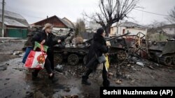 Жінки біля залишків російської військової техніки в місті Буча під Києвом, 1 березня 2022 року