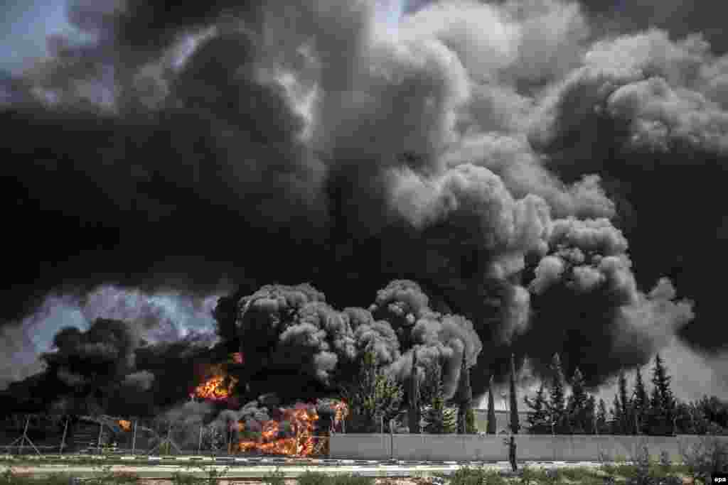 A Palestinian man takes a picture of a fire raging at Gaza's main power plant following an Israeli air strike, south of Gaza City. (epa/Oliver Weiken)