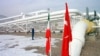 An Iranian worker stands in front of gas pipelines next to the flags of Turkey (R) and Iran. FILE PHOTO