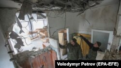 Осмотр поврежденного здания после обстрела в селе Новолуганск в Донецкой области Украины. 20 декабря 2017 года.