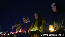 Млади луѓе држат свеќи на комеморативната служба во знак на сеќавање за жртвите од нуклеарната катастрофа во Чернобил 