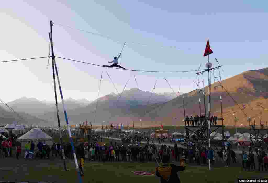 A boy runs a fast-paced high-wire act. The young man ascended the single rope on the left backward without a safety cord, though he harnessed himself in for his trick runs.