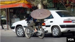 An Iranian man on a motorcycle carries a satellite dish. (file photo)