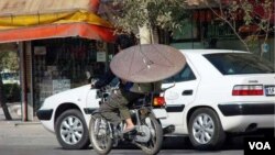 Иранский мужчина везет спутниковую антенну на мотоцикле.