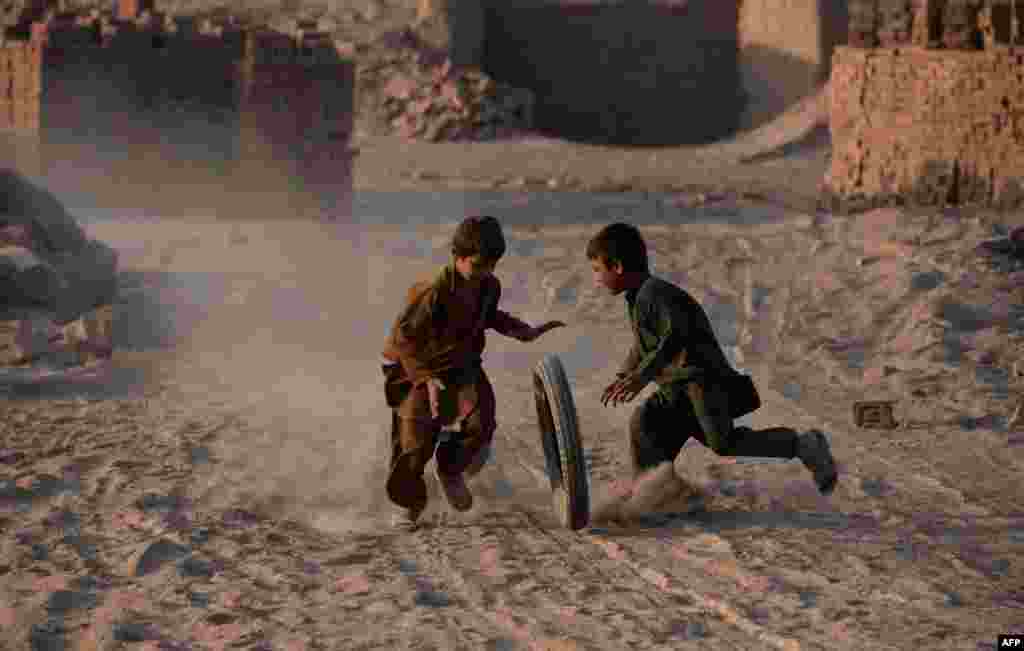 Afghan children play with a tire along a dusty road on the outskirts of Jalalabad. (AFP/Noorullah Shirzada)