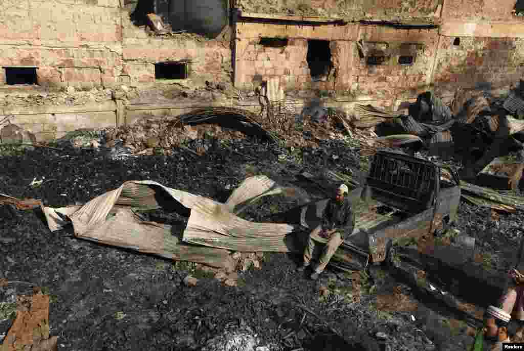 Shop owner Mohammad Hussain sits on the wreckage of a vehicle in the aftermath of a fire at a timber market in Karachi, Pakistan. More than 100 shops were destroyed. (Reuters/Akhtar Soomro)
