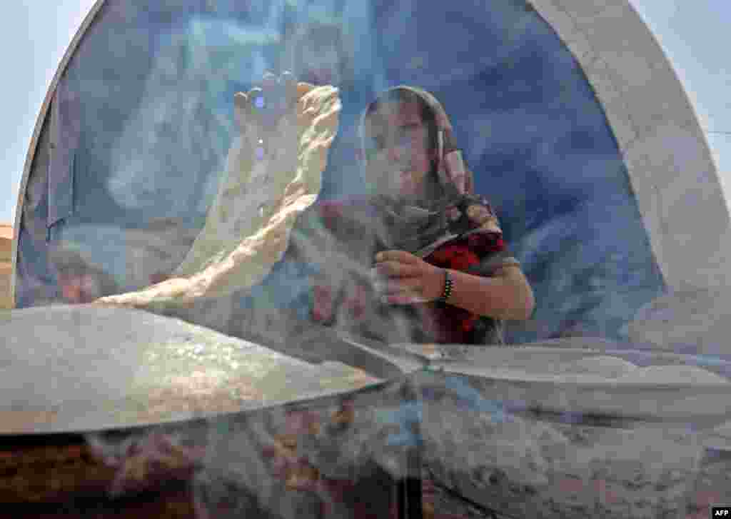 A displaced Iraqi girl bakes bread at a camp for internally displaced people south of Mosul, as government forces continue their offensive to retake the city from the Islamic State extremist group. (AFP/Karim Sahib)