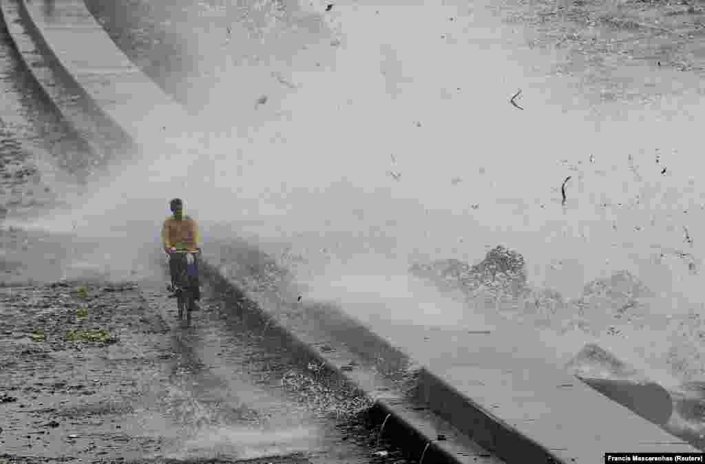 A man rides his bicycle as a wave crashes during high tide at a sea front in Mumbai, India. (Reuters/Francis Mascarenhas)