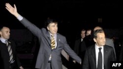 President Saakashvili, arms spread, greets French President Sarkozy in Tbilisi