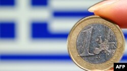Greece -- A 1 euro coin in front of a Greek national flag - generic