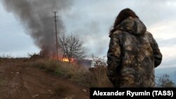 Місцева жителька дивиться на будинок, що палає, в районі бойових дій поблизу міста Лачин, листопад 2020 року 