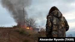 A local resident looks at a burning house in the town of Lachin (Berdzor), November 30, 2020.