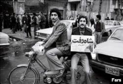 A man waves a newspaper announcing “The Shah Left” during demonstrations in Tehran in 1979.