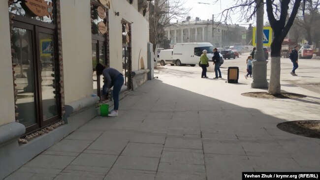 Девушка отмывает окна кафе от строительной пыли