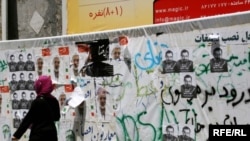 An Iranian woman walks past campaign posters in Tehran on June 8.