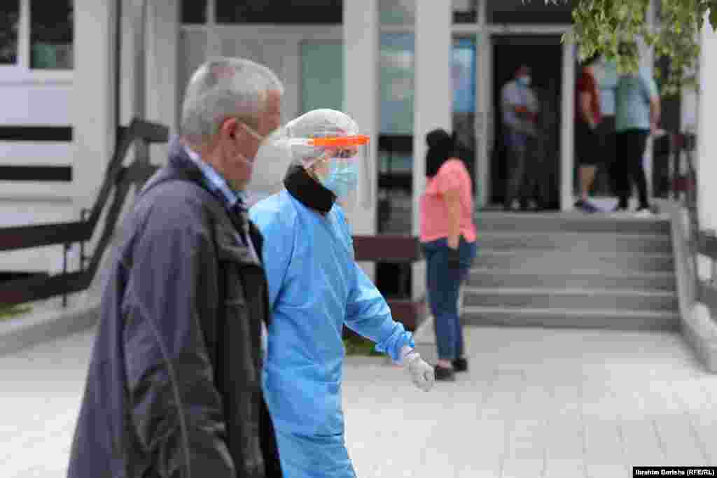 Një person dhe një punonjëse shëndetësore pranë Klinikës Infektive në Prishtinë.&nbsp;