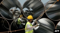 Workers pull a rope next to pipes during the arrival ceremony of the first Trans-Adriatic Pipeline pipes in Spitalle, near Durres, Albania, in April 2016.