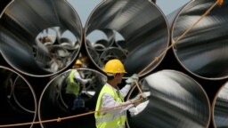 Workers pull a rope next to pipes during the arrival ceremony of the first Trans-Adriatic Pipeline pipes in Spitalle, near Durres, Albania, in April 2016.