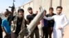 An IS militant (left) stands next to residents as they hold pieces of wreckage from a Syrian war plane after it crashed in Raqqa in September, 2014.